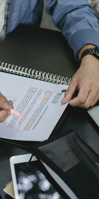 From above of crop anonymous male students underline information in text of document while making task during seminar preparation
